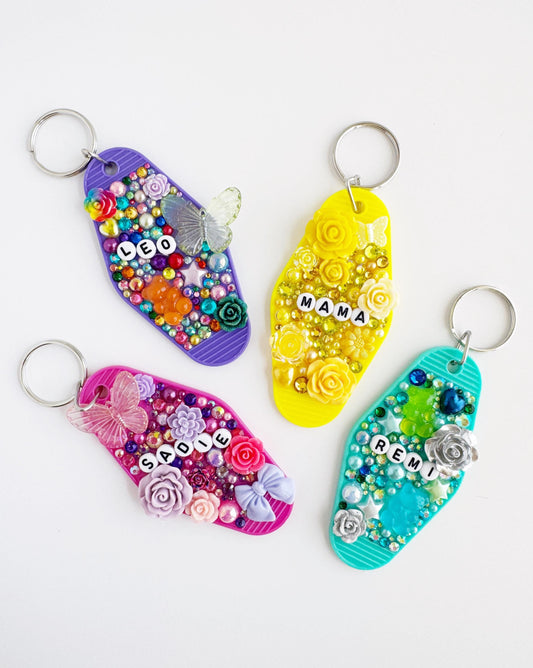 four colorful keychains with various decorative elements such as flowers, beads, and butterflies.