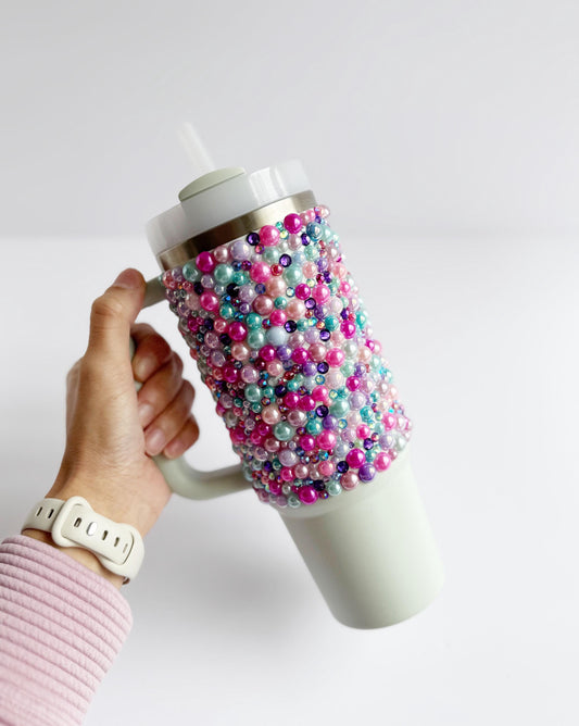 a person holding a coffee cup with beads on it