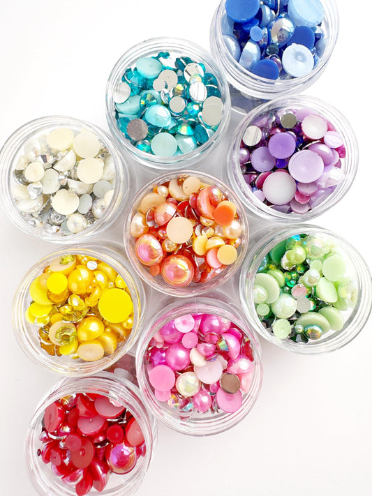 A collection of small glass jars filled with colorful beads, buttons, and sequins arranged in a visually appealing manner.