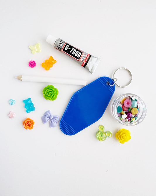 various craft supplies, including a tube of glue, a keychain, a pencil, and a small container filled with colorful beads.