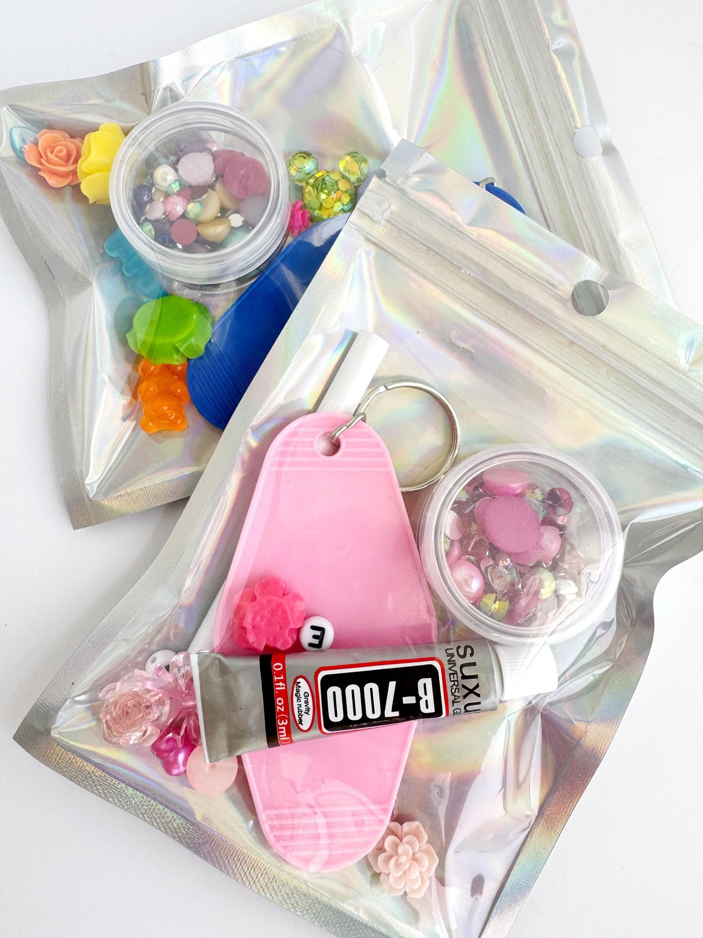 various colorful items, including a pink keychain, a tube of glue, and a clear container filled with small objects.