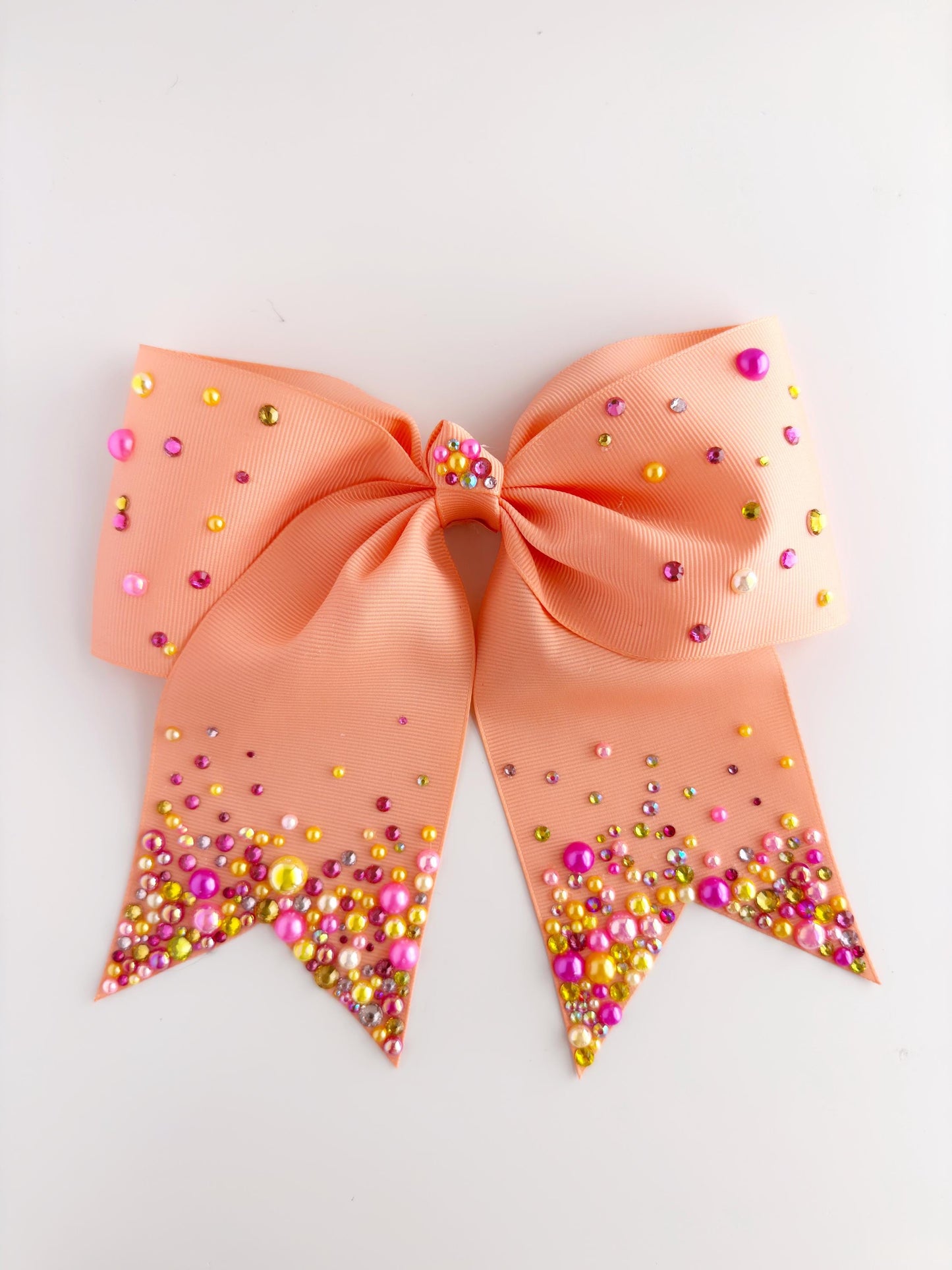 A peach-colored ribbon adorned with multicolored beads, including pink, yellow, and green, is displayed against a white background.