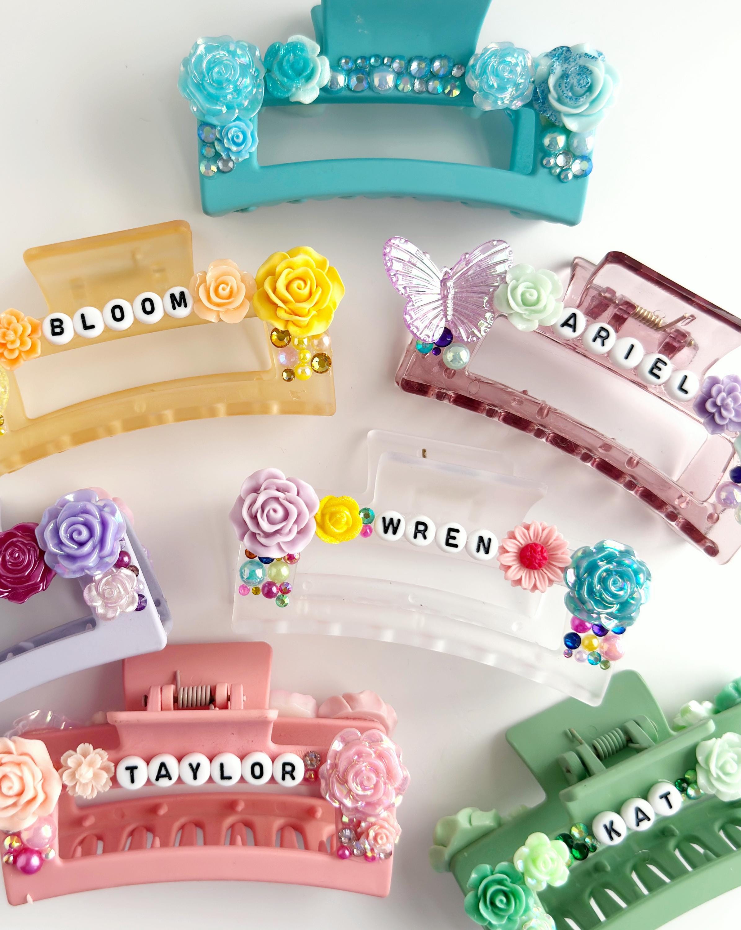 a collection of colorful plastic hair clips adorned with various decorative elements such as flowers, butterflies, and the names of the users.