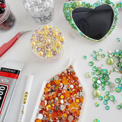 various craft supplies, including a pair of colorful beads, a pair of sunglasses with a heart-shaped frame, and a pair of scissors.