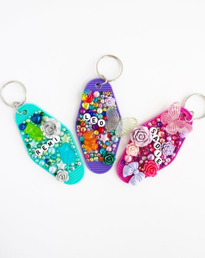 three colorful keychains with various decorative elements, including beads, flowers, and butterflies.