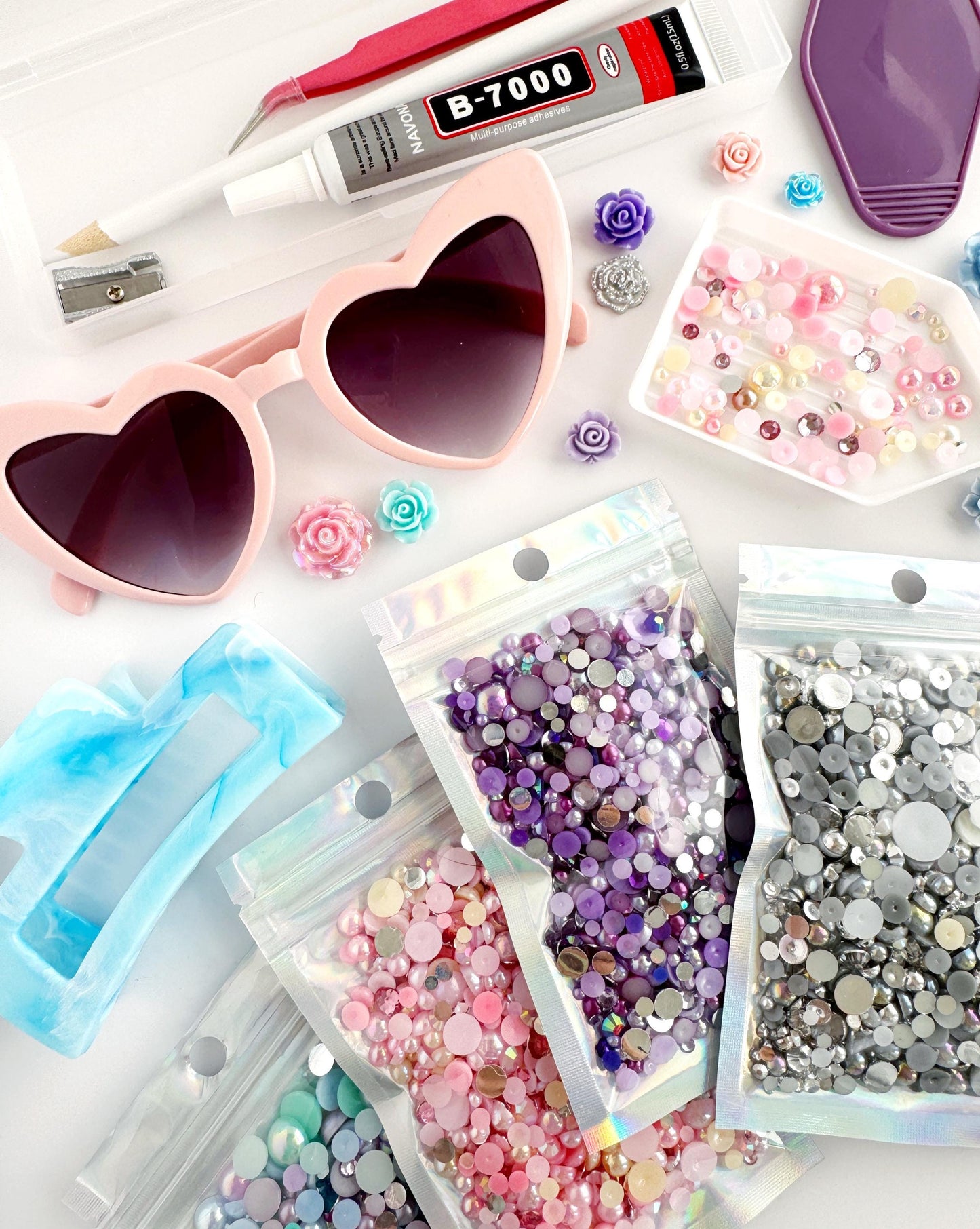 A collection of various craft supplies, including heart-shaped sunglasses, beads, and other embellishments, arranged on a surface.