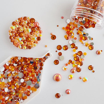 a variety of colorful beads and stones, including orange, yellow, and pink, scattered across a white background.