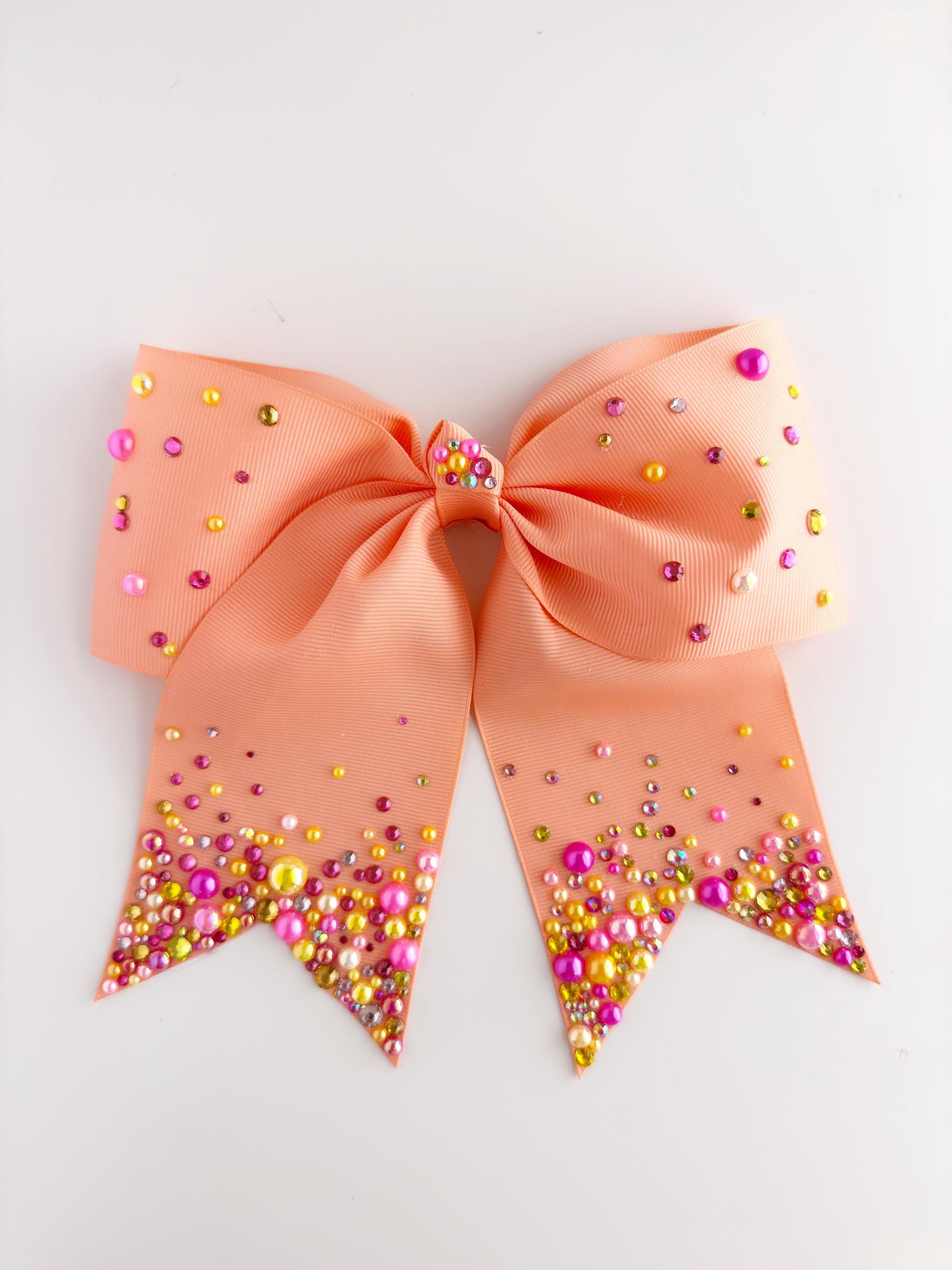 A peach-colored ribbon adorned with multicolored beads, including pink, yellow, and green, is displayed against a white background.