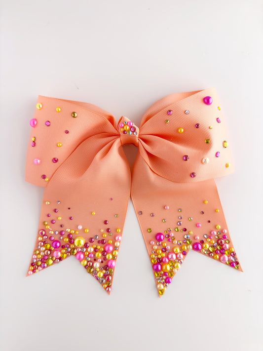 A peach-colored ribbon adorned with multicolored beads, including pink, yellow, and green, is displayed against a white background.