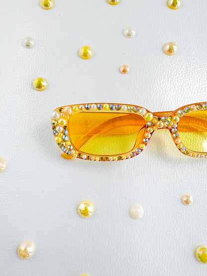 a pair of yellow sunglasses with jewels on them