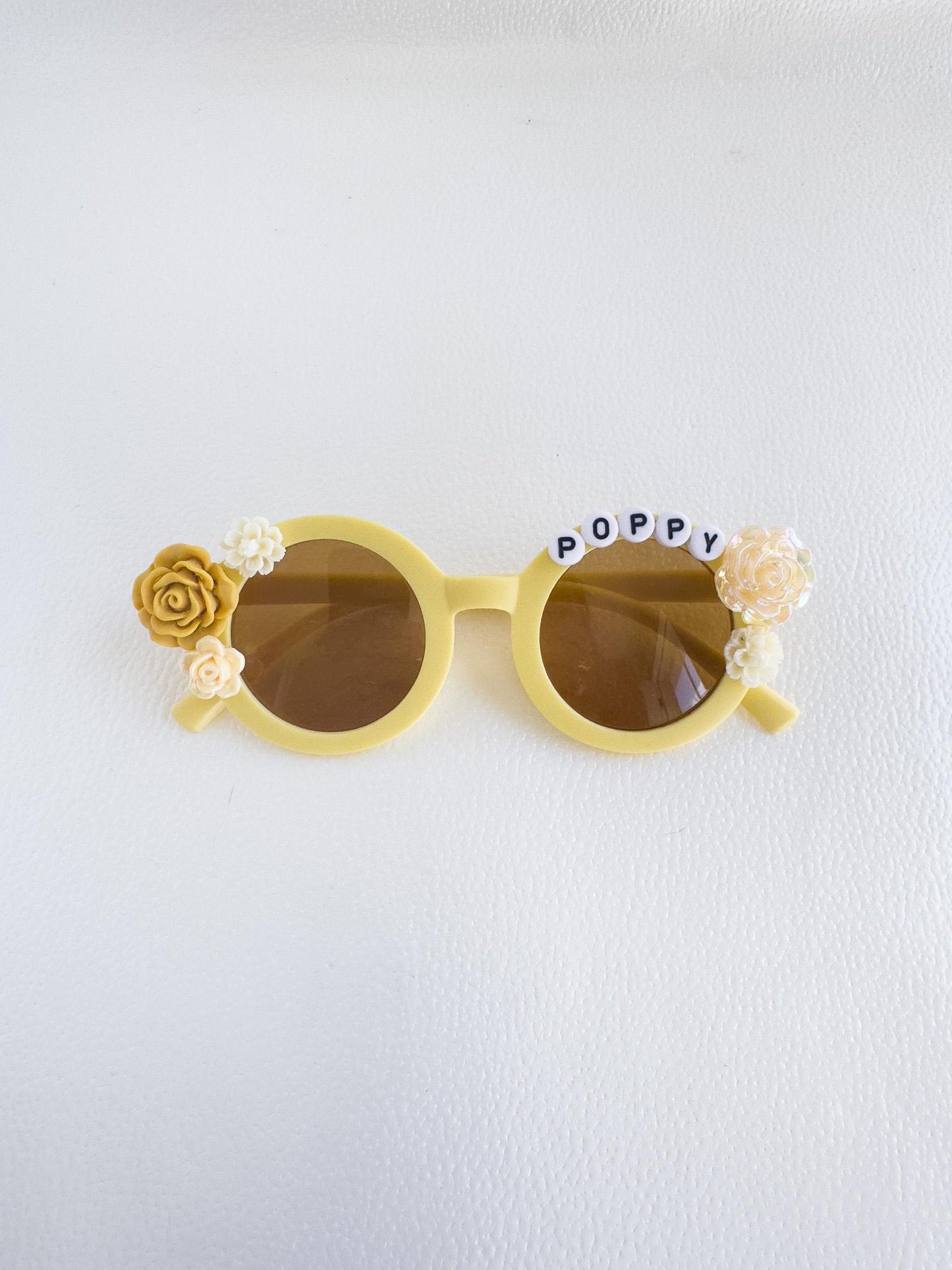 a pair of yellow sunglasses with flowers on them